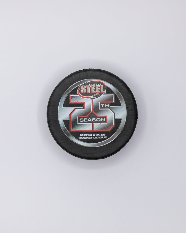 black hockey puck with Chicago Steel logo and 25th season graphic on front - front lay flat