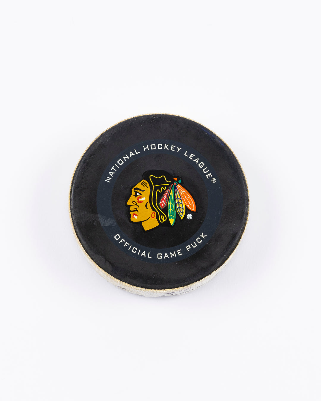 game-used hockey goal puck shot by former Chicago Blackhawks player Alex DeBrincat - front lay flat