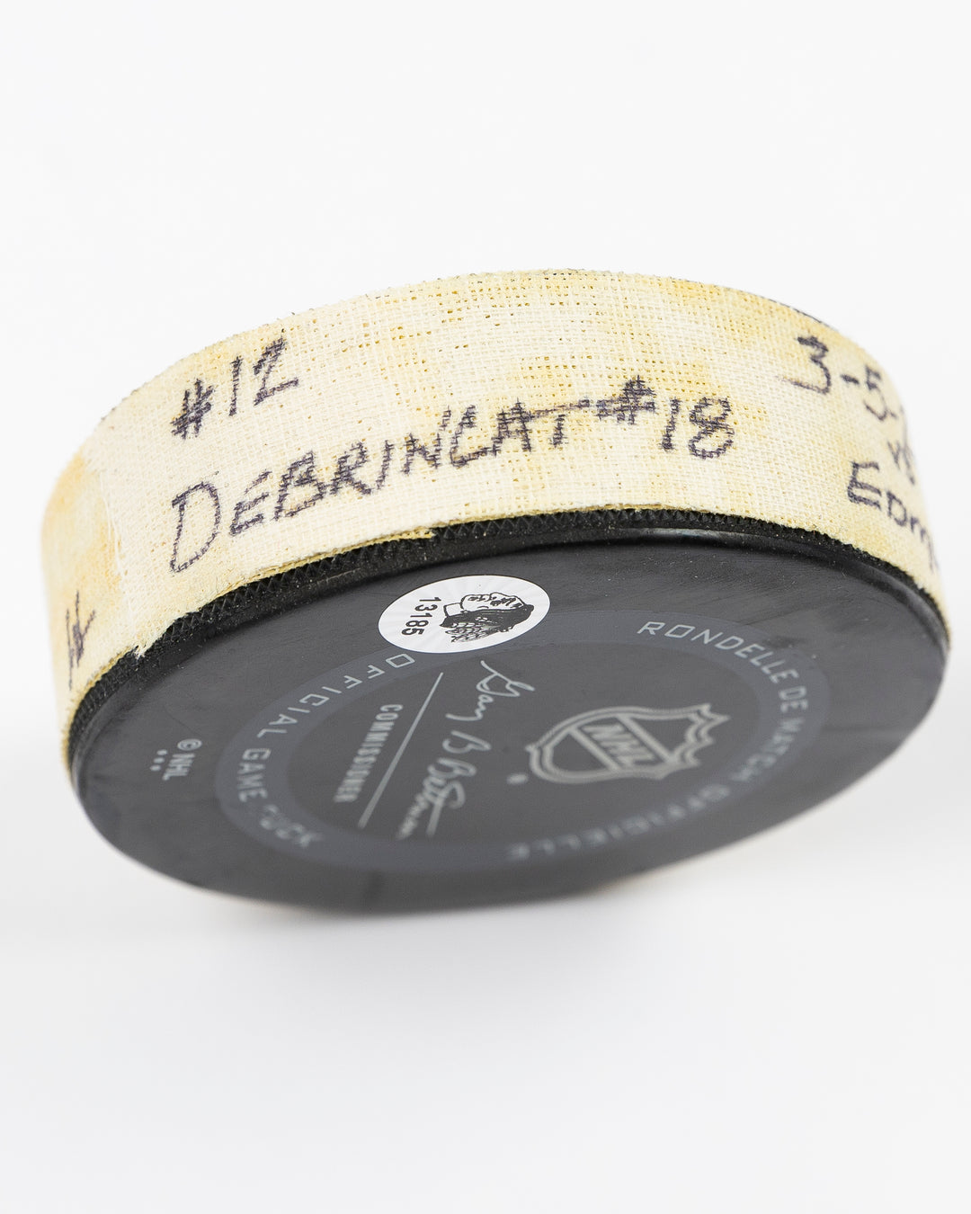 game-used hockey goal puck shot by former Chicago Blackhawks player Alex DeBrincat - detail tape lay flat