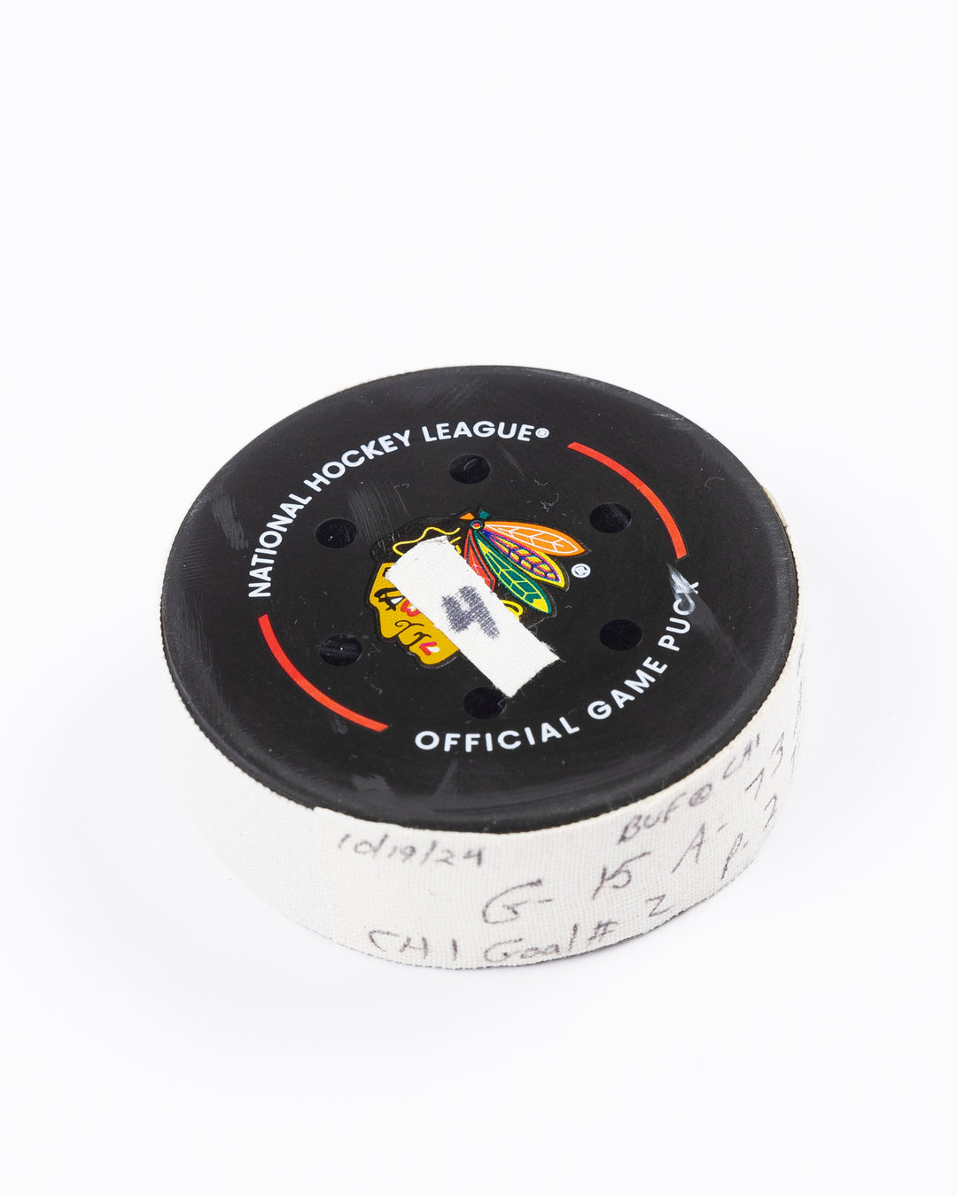 game used hockey goal puck scored by Chicago Blackhawks player Craig Smith on game on October 19, 2024 - front angled lay flat