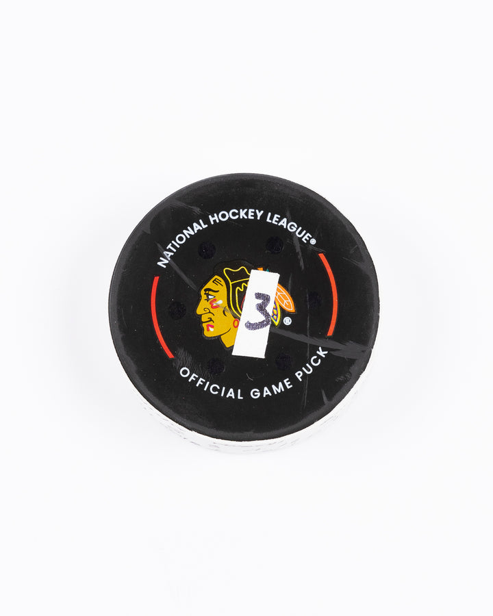 game used hockey goal puck scored by Chicago Blackhawks player Ryan Donato during game on October 22, 2024 - front lay flat