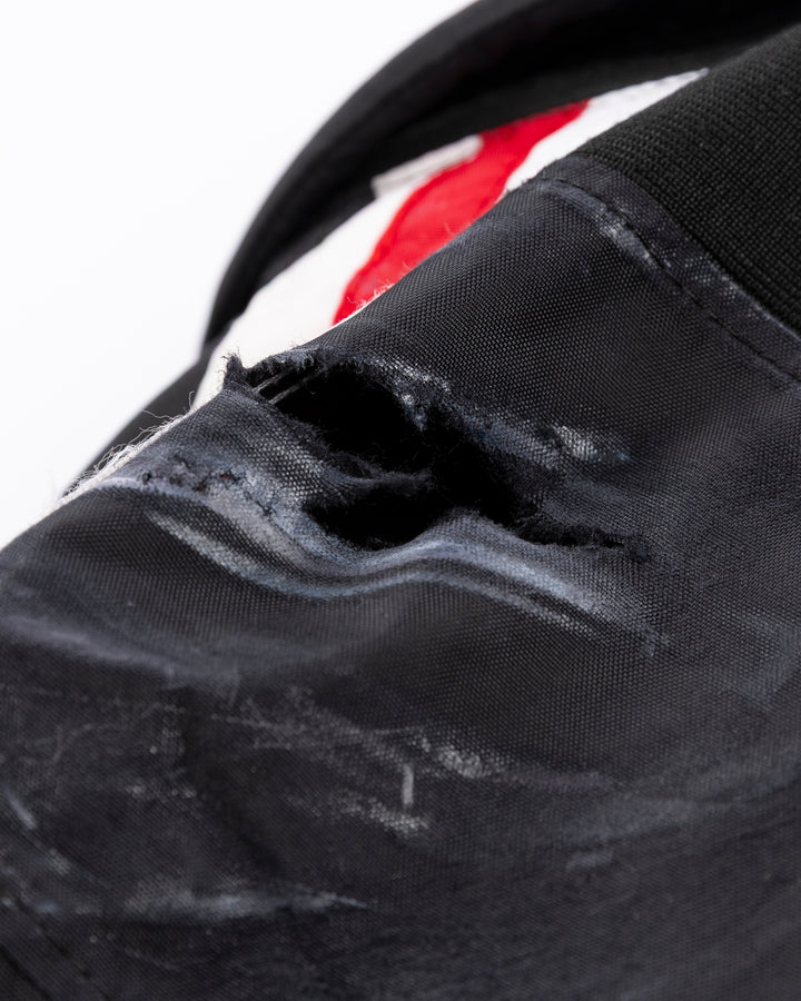 black CCM hockey pants used by Chicago Blackhawks player Jason Dickinson - distressing detail lay flat