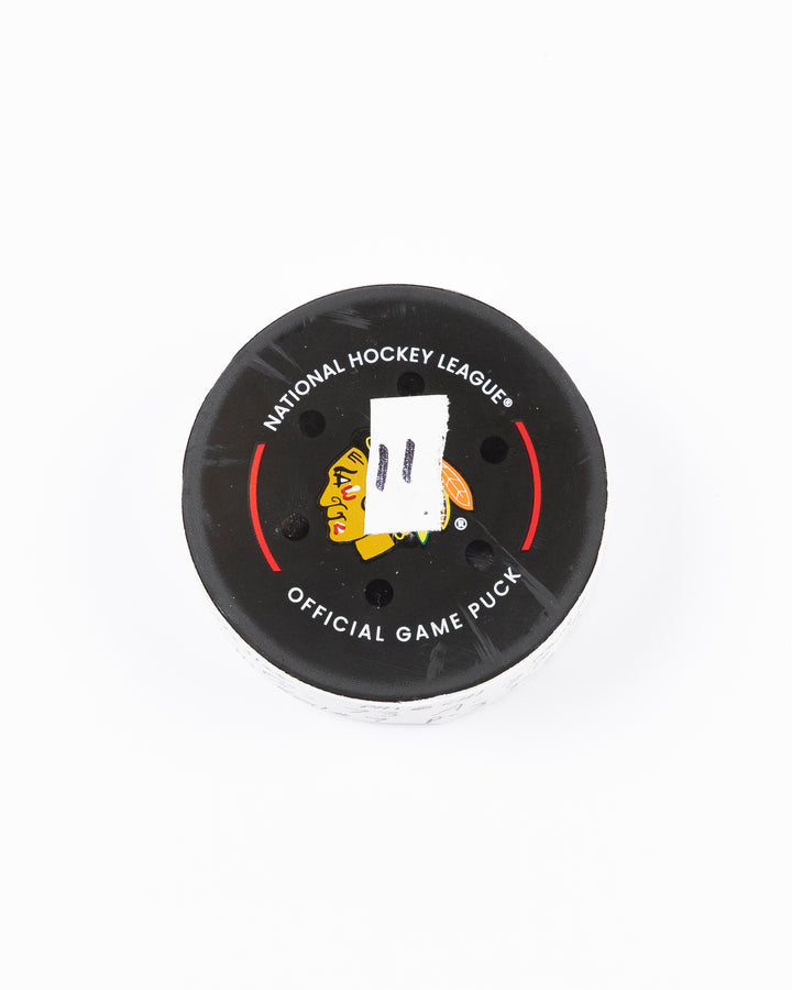 official game used hockey goal puck used by Chicago Blackhawks player Lukas Reichel - front lay flat