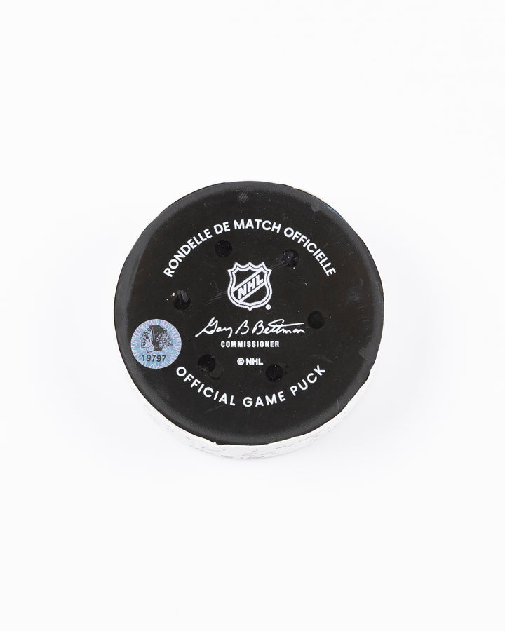 official game used hockey goal puck used by Chicago Blackhawks player Lukas Reichel - back lay flat