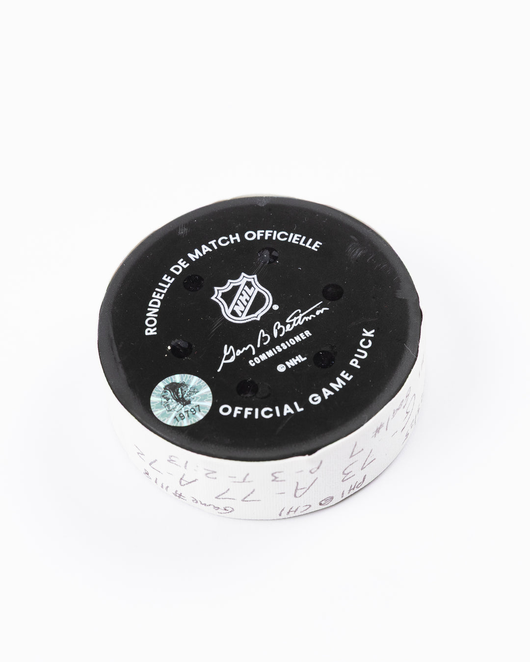 official game used hockey goal puck used by Chicago Blackhawks player Lukas Reichel - back angle lay flat