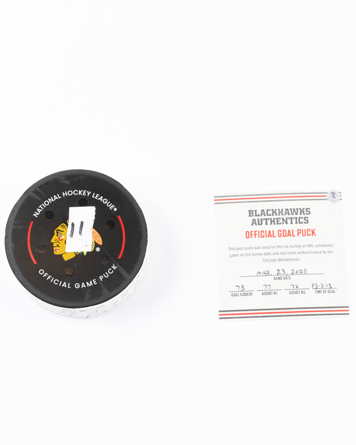 official game used hockey goal puck used by Chicago Blackhawks player Lukas Reichel - front lay flat puck and certificate