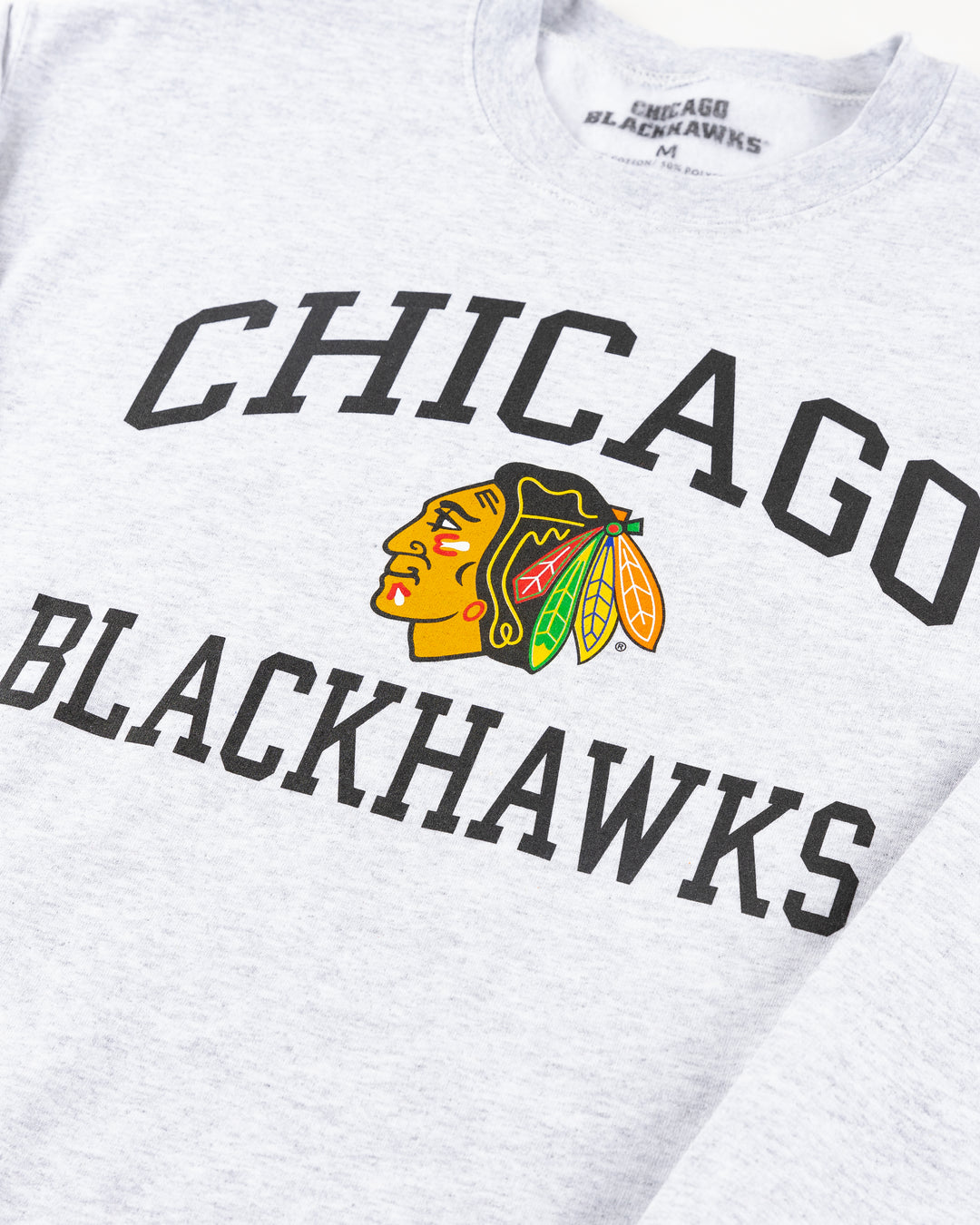 grey Chicago Blackhawks crewneck with wordmark and primary logo on chest and secondary logo on left wrist - detail front lay flat