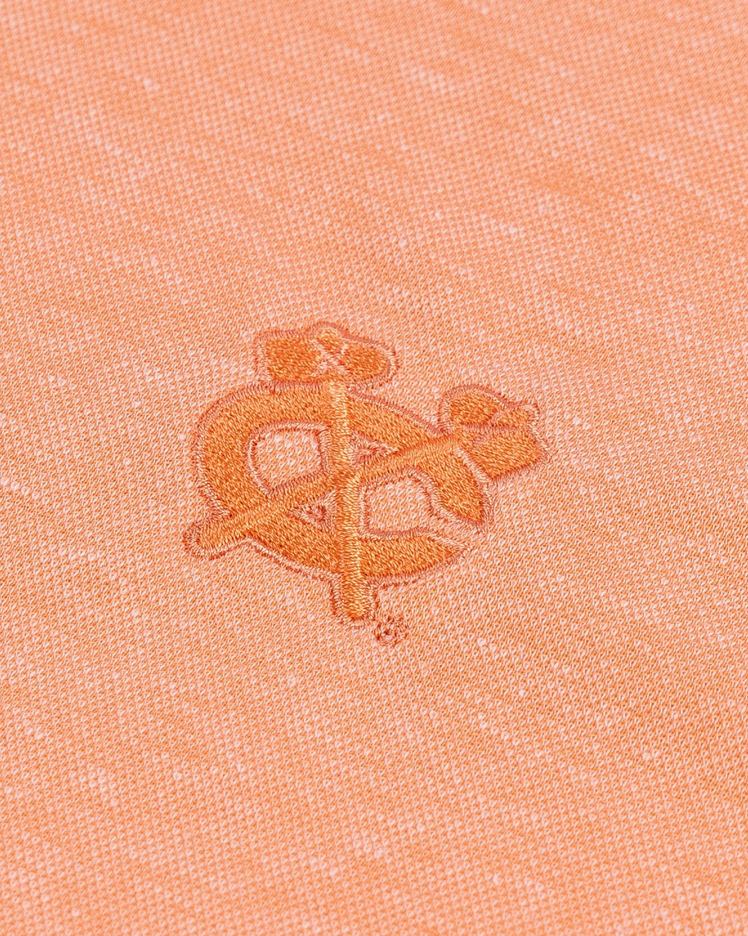 orange TravisMathew polo with Chicago Blackhawks secondary logo embroidered on left chest - detail lay flat