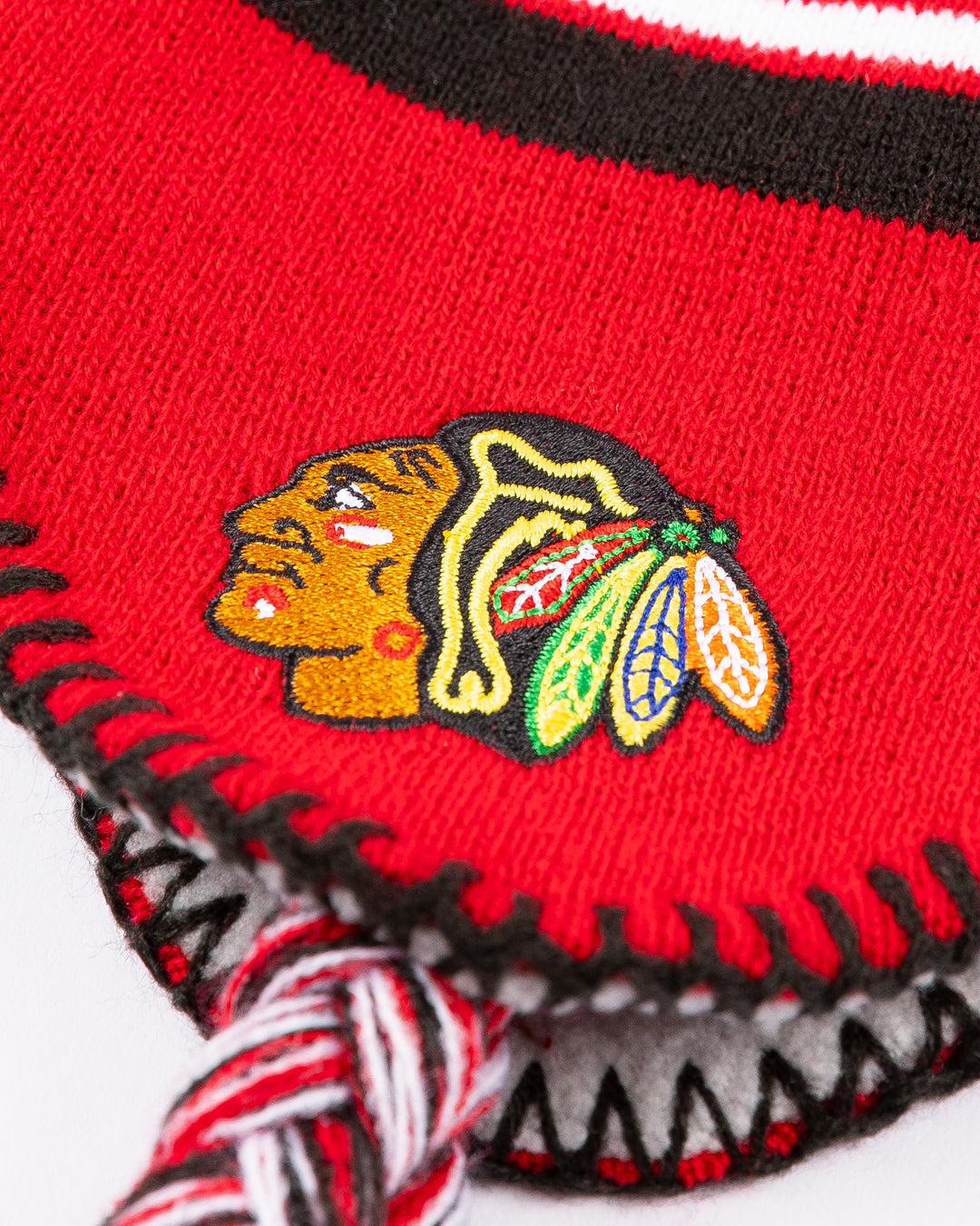 red youth knit hat with tassels and Chicago Blackhawks wordmark on front and Chicago Blackhawks primary logo and NHL logo embroidered on sides - detail lay flat