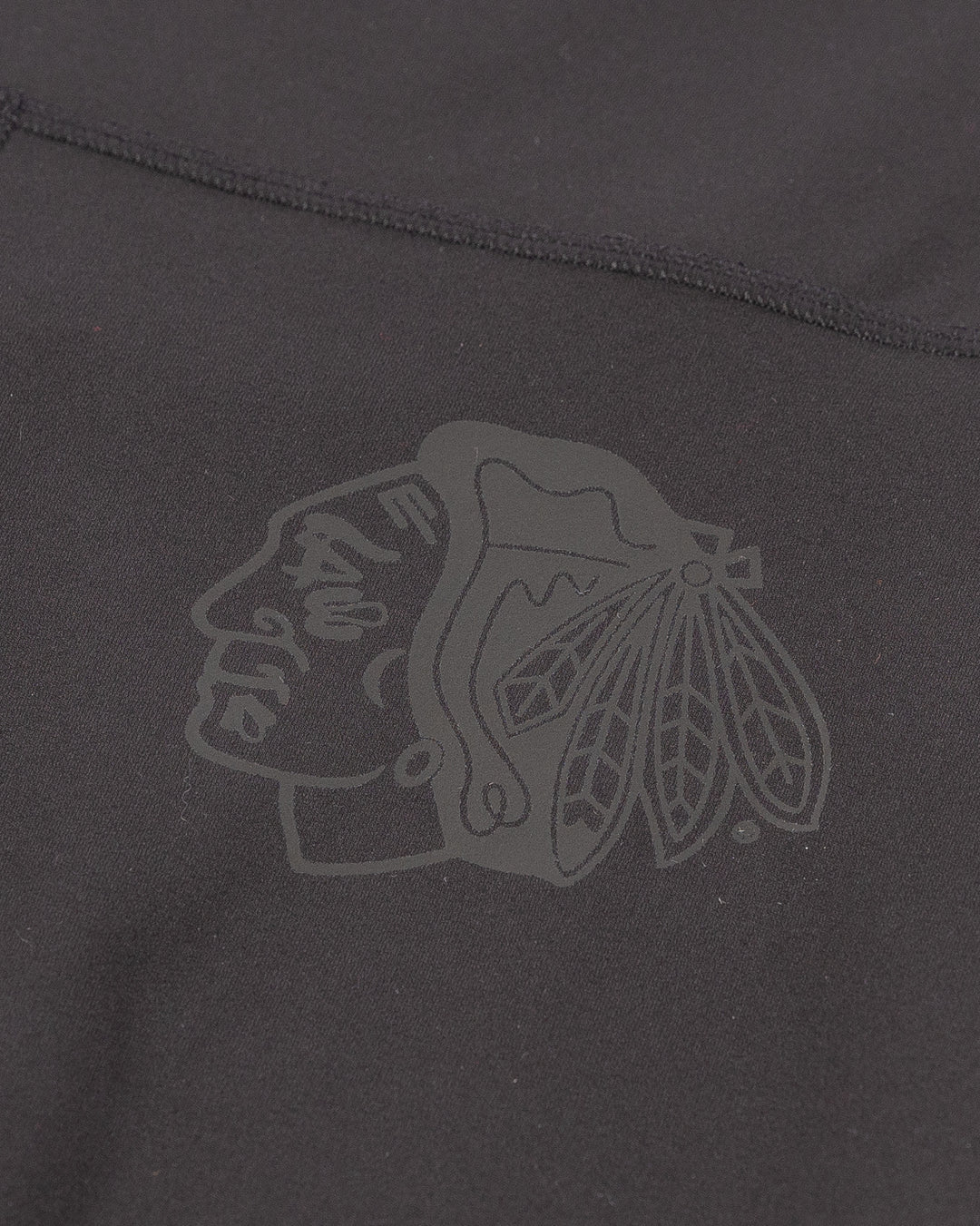 black lululemon yoga pants with subtle flare at hem and tonal Chicago Blackhawks primary logo printed on left leg - detail lay flat