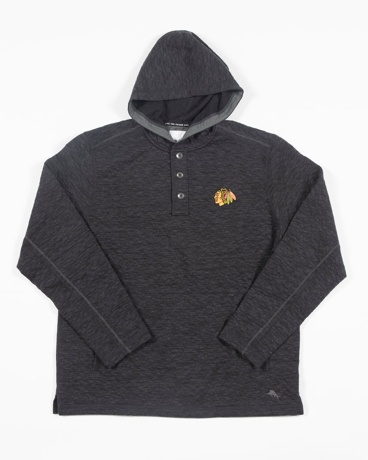 black Tommy Bahama hoodie with half button closure with Chicago Blackhawks primary logo embroidered on left chest - front lay flat