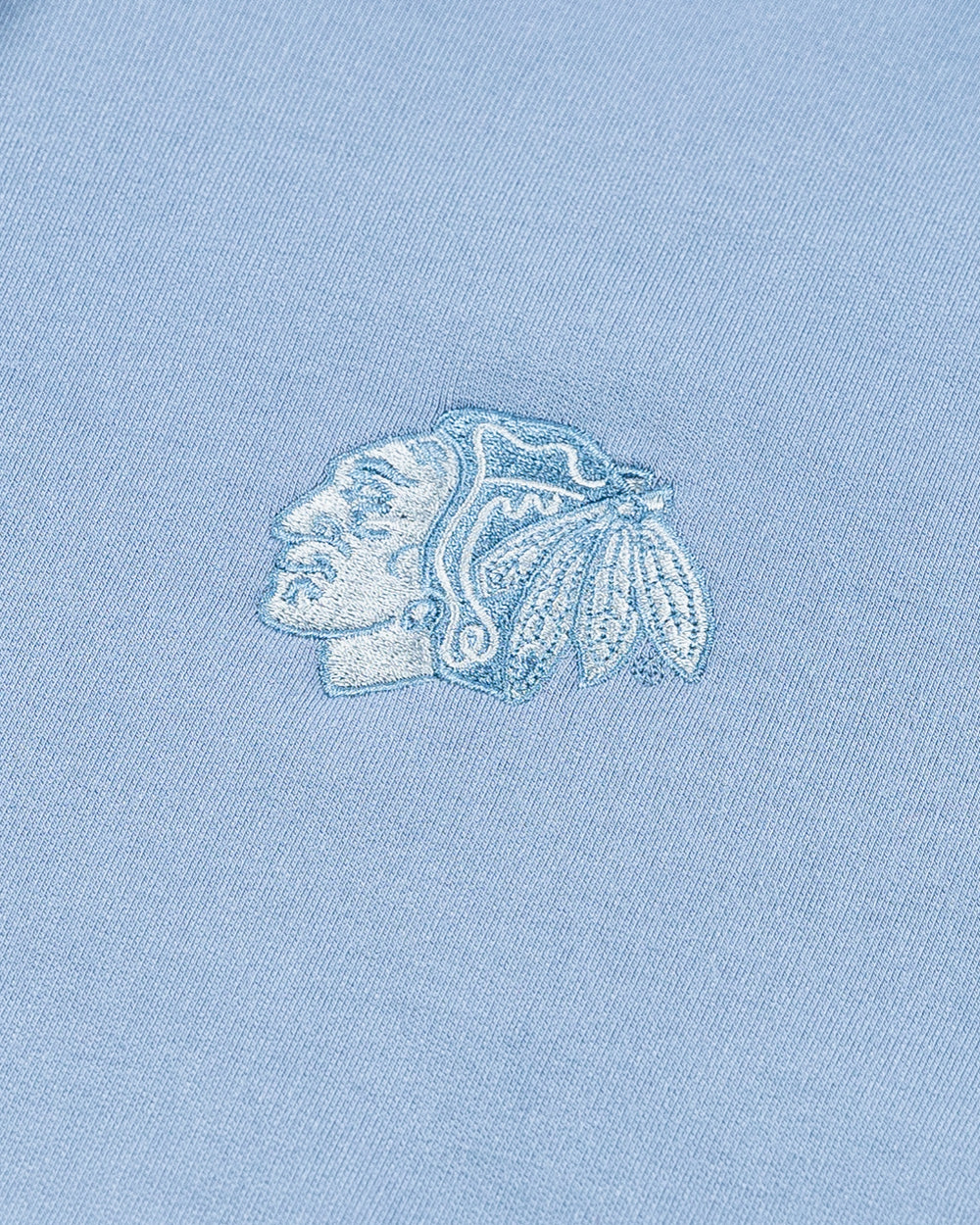 light blue TravisMathew hoodie with Chicago Blackhawks tonal primary logo embroidered on left chest - detail lay flat