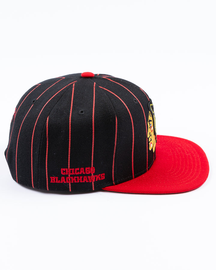 black and red Mitchell & Ness snapback cap with embroidered Chicago Blackhawks primary logo embroidered on front - right side lay flat