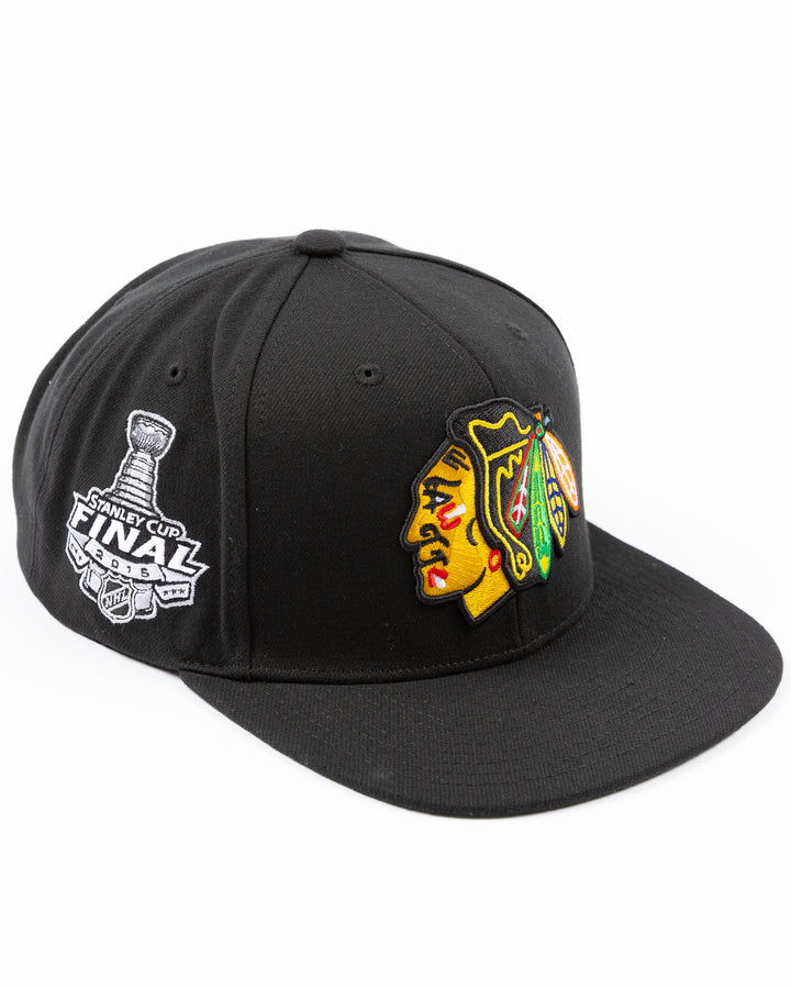 black Mitchell & Ness snapback cap with Chicago Blackhawks primary logo embroidered on front and 2015 Stanley Cup championship patch on right side - right angle lay flat