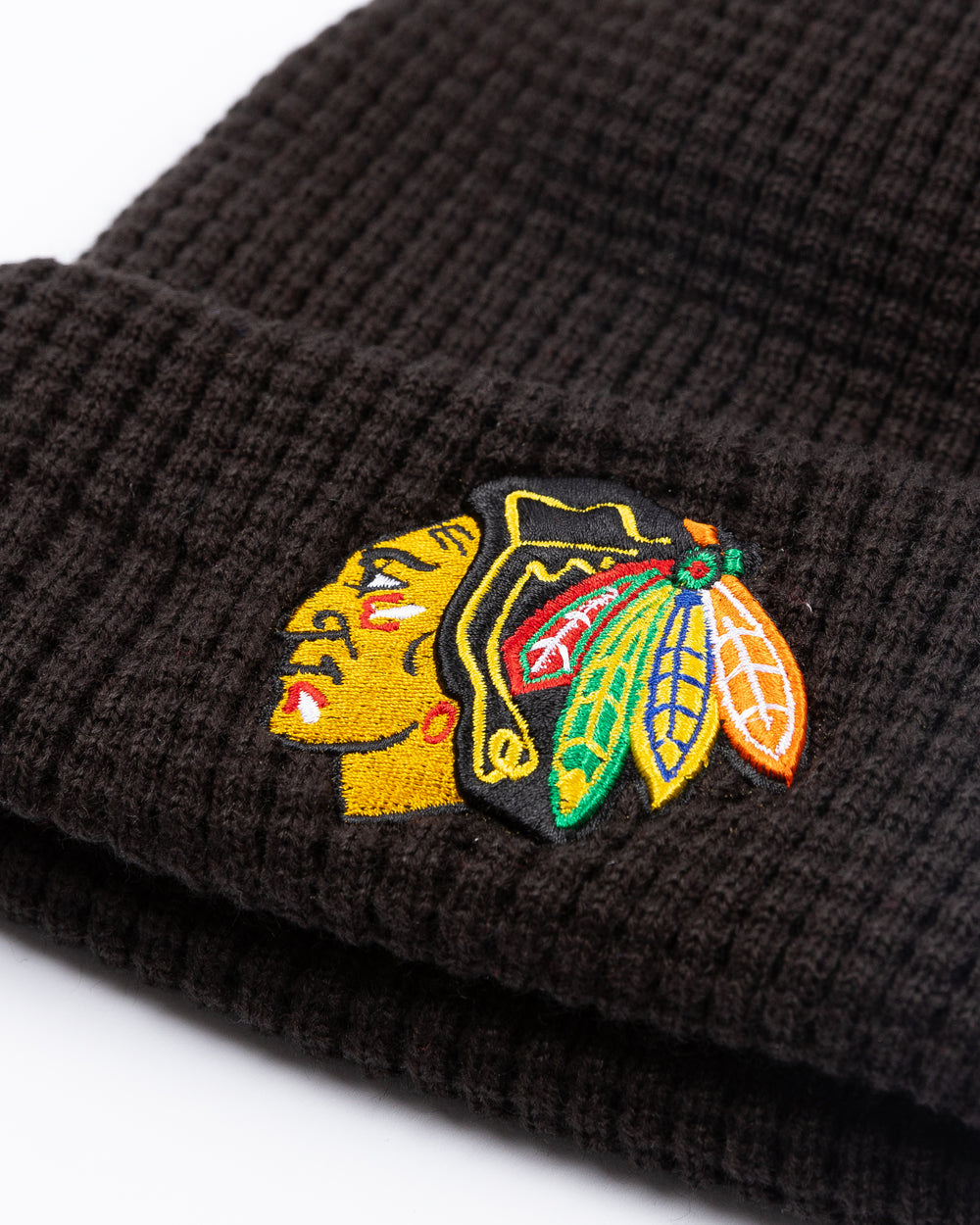 youth New Era black knit waffle beanie with embroidered Chicago Blackhawks primary logo on front cuff - detail lay flat