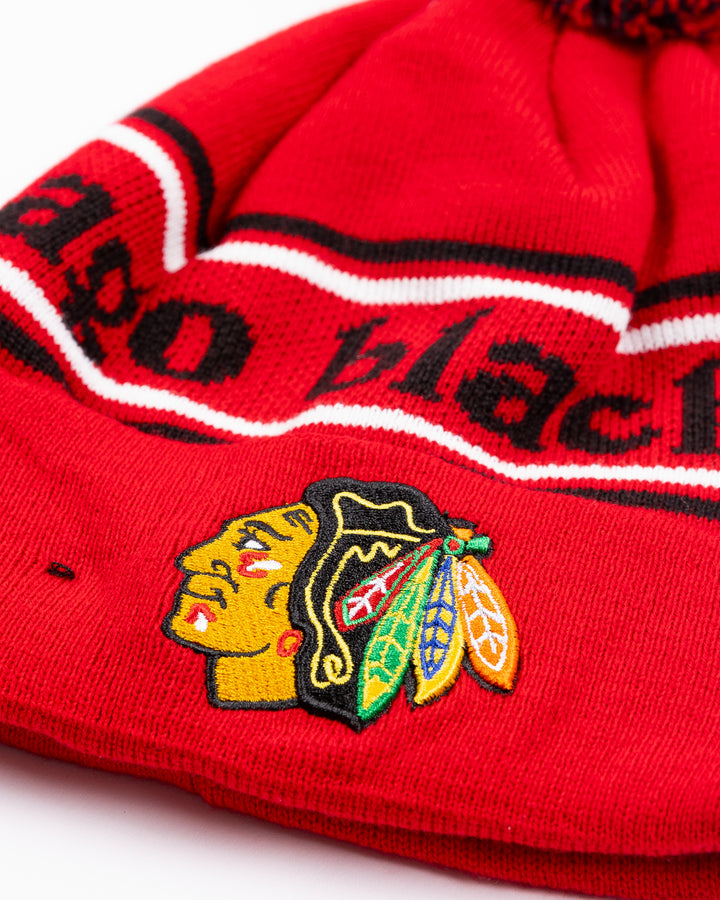 red New Era beanie with two tone pom and Chicago Blackhawks wordmark across front and embroidered primary logo on front cuff - detail lay flat