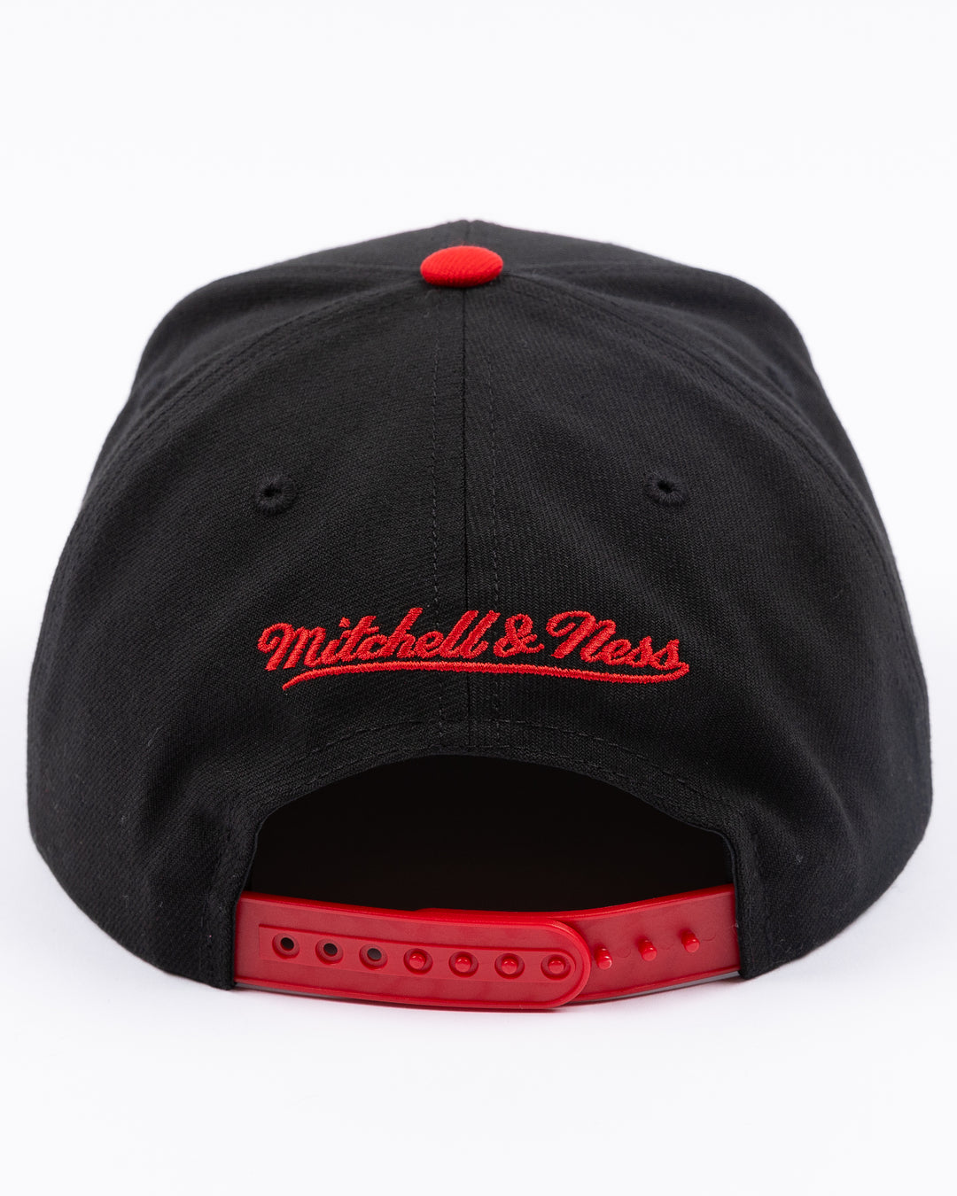 two tone red and black Mitchell &amp; Ness snapback with embroidered primary logo on front - back lay flat