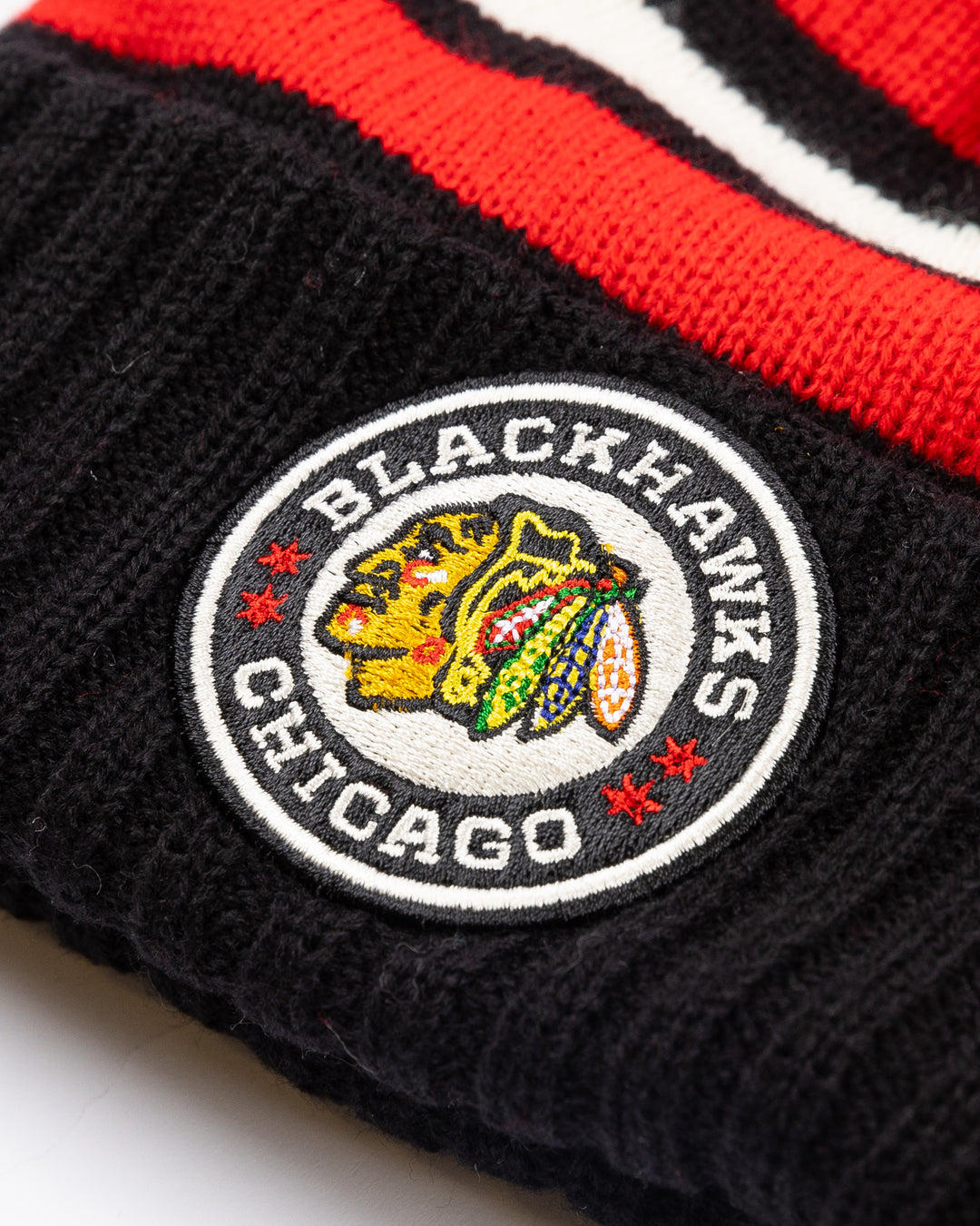 striped black white and red American Needle pom knit hat with multi color pom on top and Chicago Blackhawks and NHL Winter Classic patches embroidered on front and back - front detail lay flat