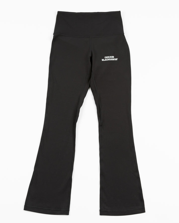 black lululemon legging pants with flare at hem and Chicago Blackhawks wordmark on left thigh - front lay flat