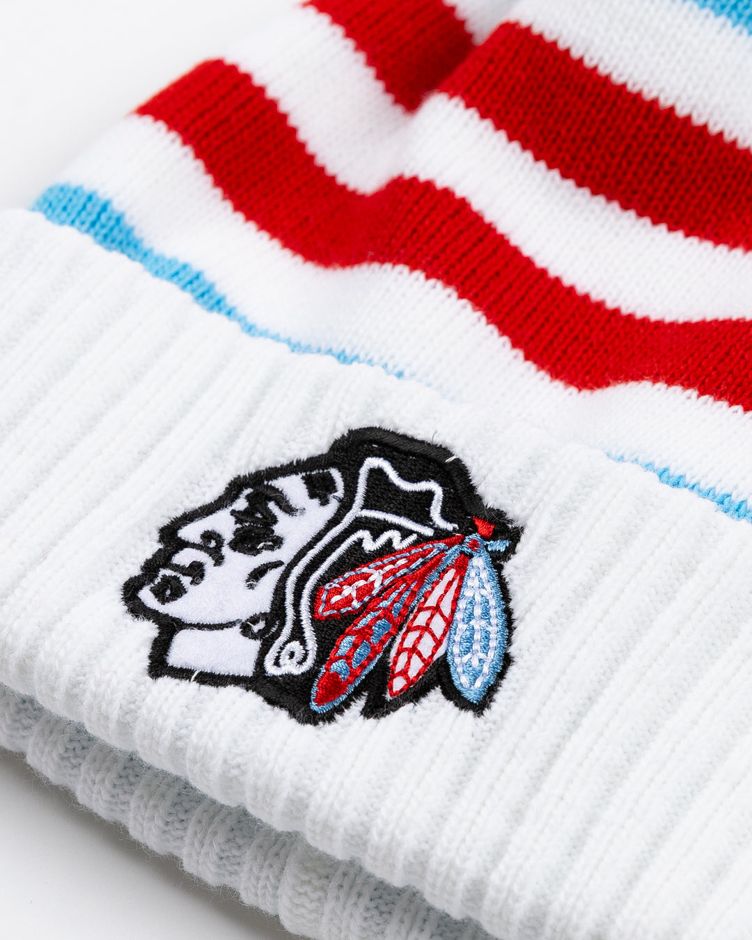 red, white and blue striped knit hat with Chicago Blackhawks primary logo embroidered on front cuff and multi-color pom on top - front detail lay flat