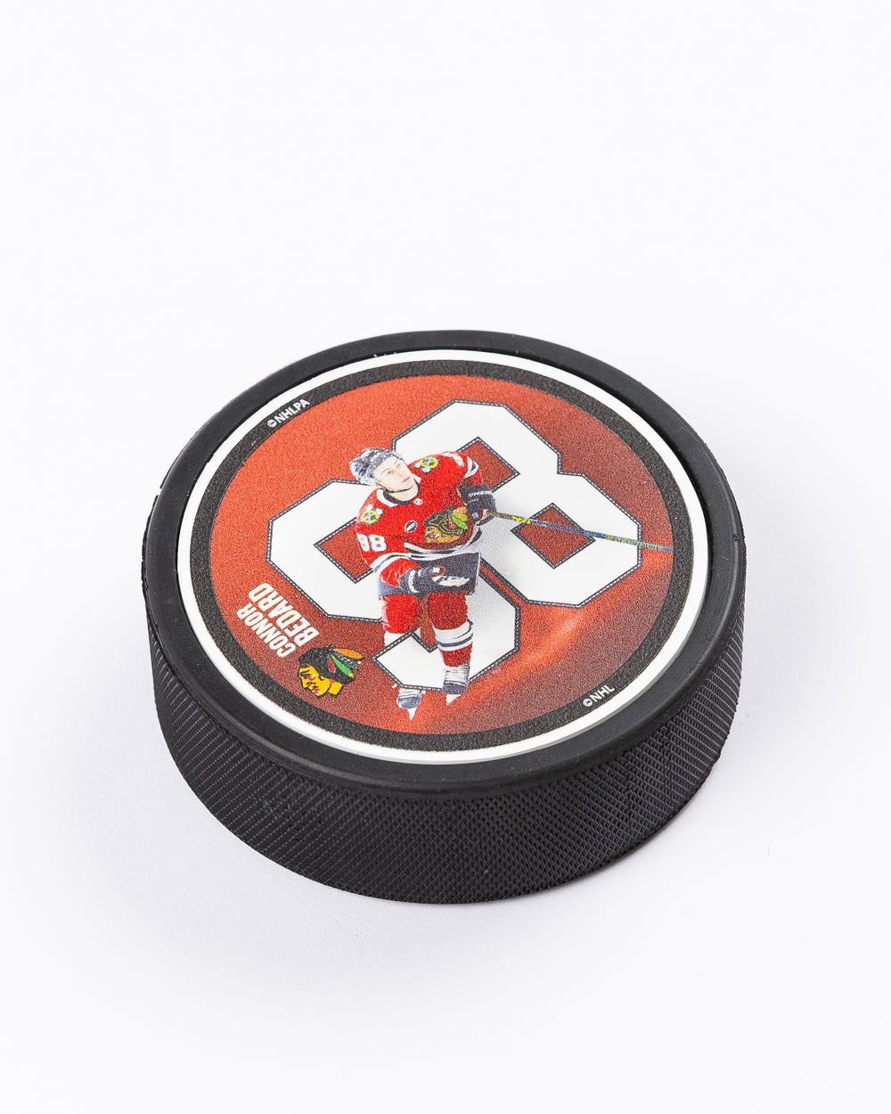 hockey puck with Connor Bedard name and number with action photo and Chicago Blackhawks primary logo - angled front lay flat