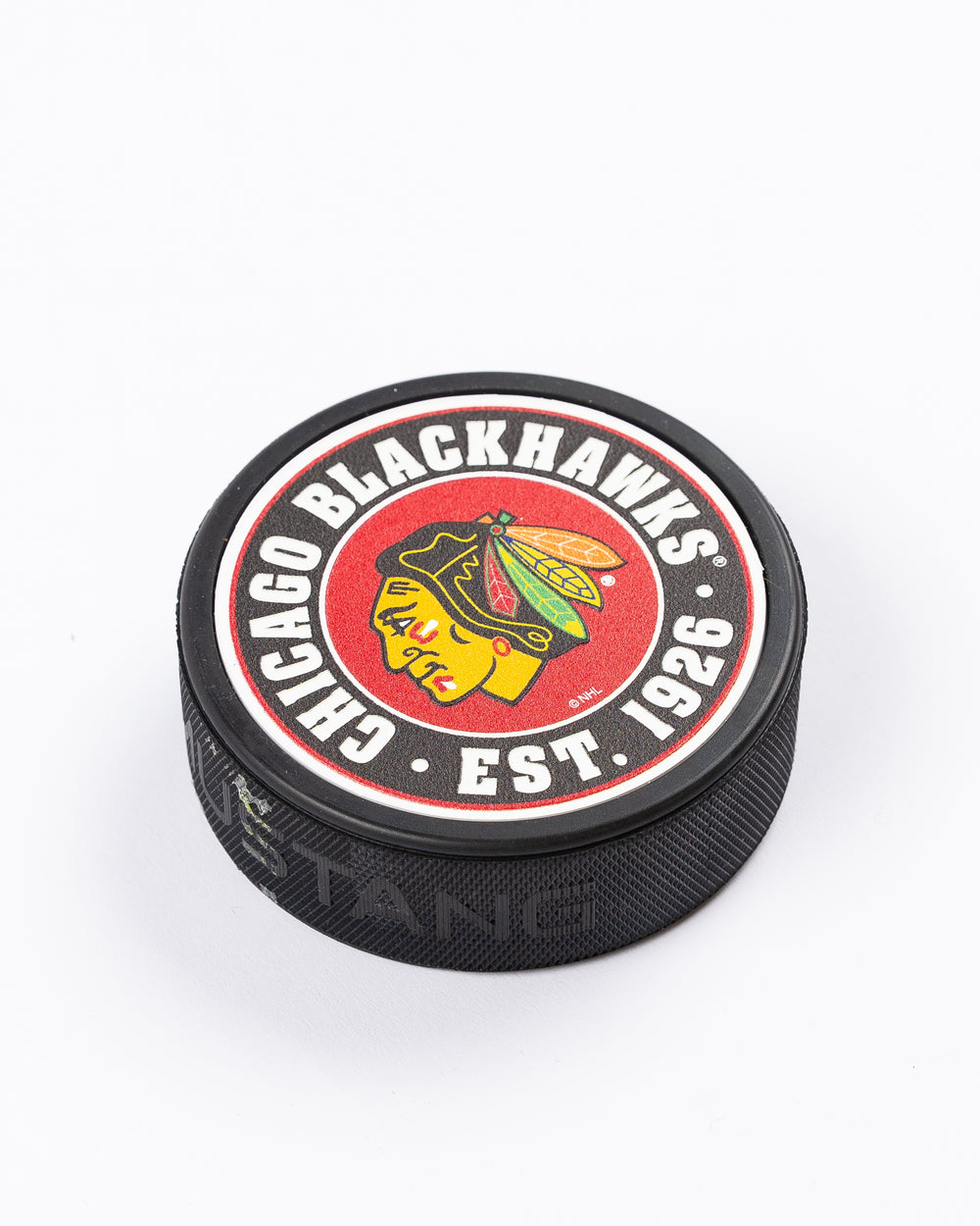 hockey puck with Chicago Blackhawks primary logo and established 1926 word graphic surrounding it - front angle lay flat