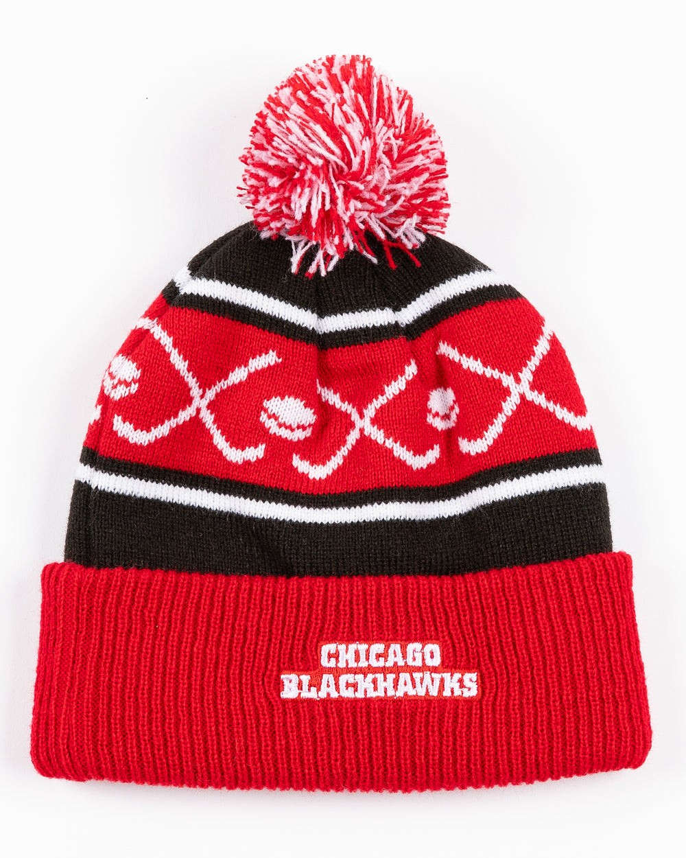 red white and black infant sized knit beanie with red and white pom and hockey stick and puck graphic with Chicago Blackhawk primary logo embroidered on front cuff - back lay flat